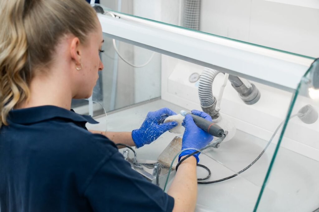 Tandtechnicus werkt een gebit met de hand af