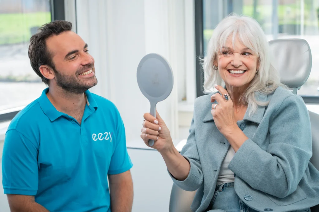 Patiënte bekijkt haar nieuwe gebit in de spiegel
