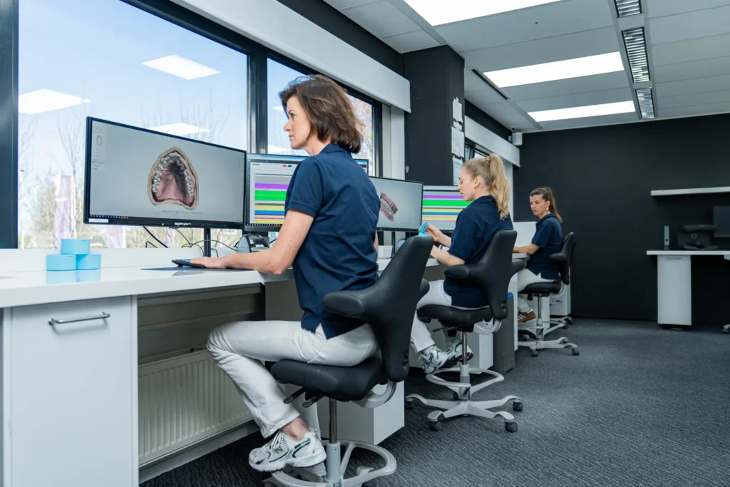 Tandtechnici ontwerpen een gebit op het scherm in het lab van Eezy